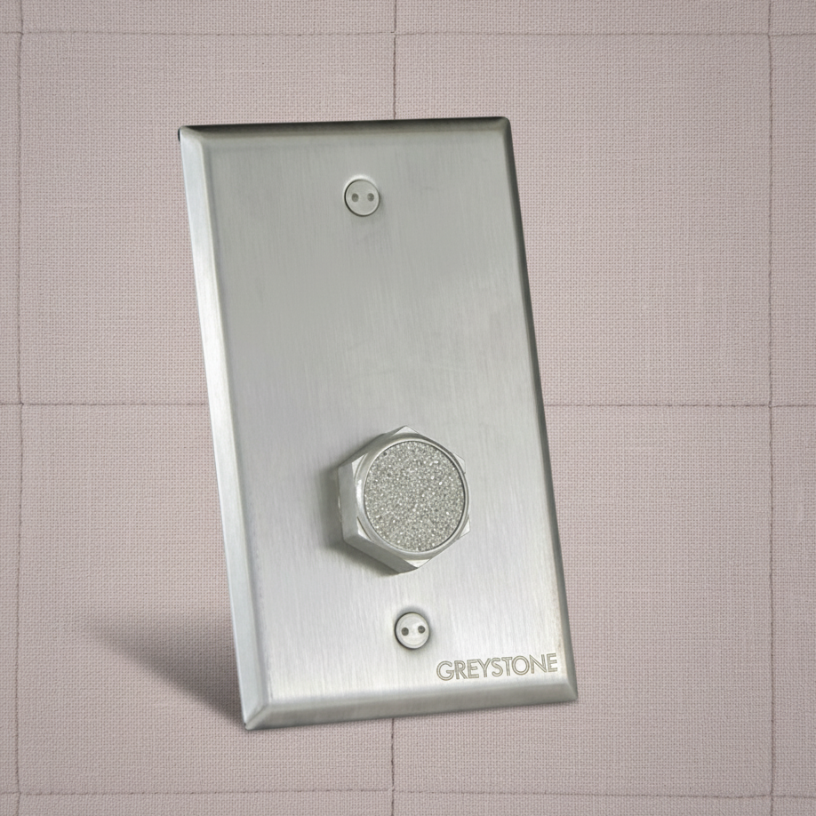 Metallic wall sensor plate with 'Greystone' branding on a tiled wall background