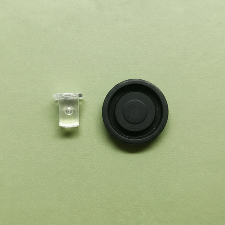 Small black round button and clear pin on a green background